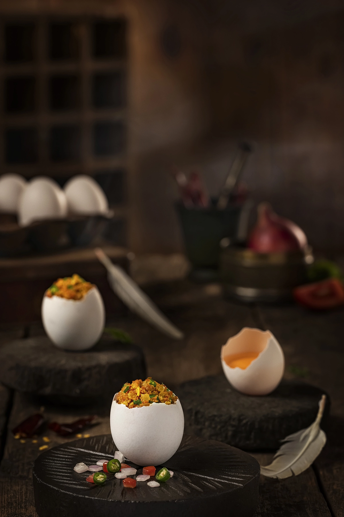 Stuffed eggs served in cracked eggshells on dark stone bases with a moody kitchen background.